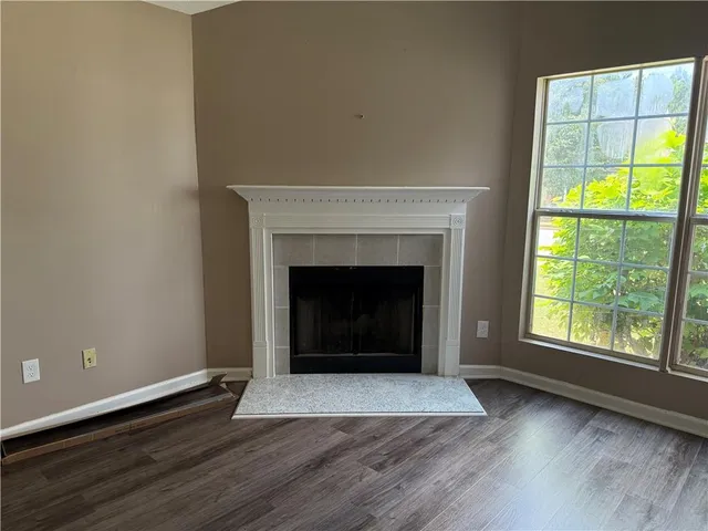 an empty room with wooden floor fireplace and windows