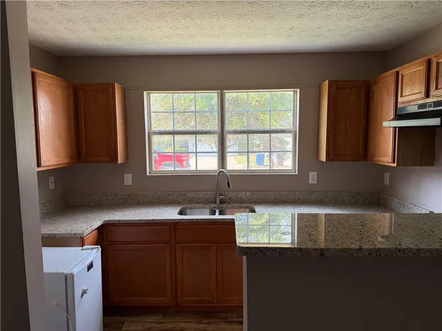 a kitchen with granite countertop a sink and a stove top oven