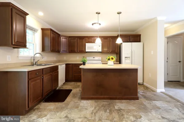 a kitchen with stainless steel appliances granite countertop a sink a stove a refrigerator a center island and cabinets