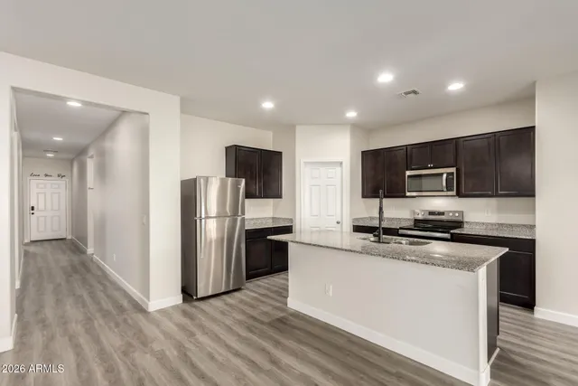 a kitchen with stainless steel appliances a stove a sink a refrigerator a microwave and cabinets