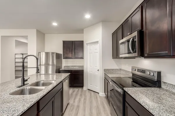 a kitchen with stainless steel appliances granite countertop a sink stove microwave and refrigerator
