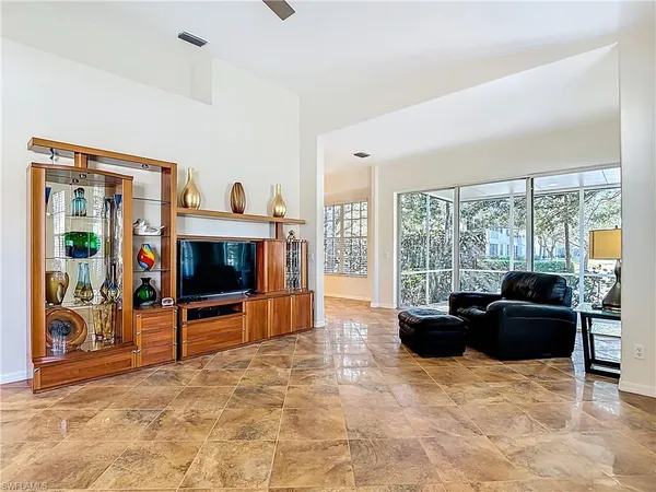 a living room with furniture a flat screen tv and floor to ceiling window