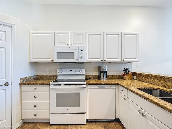 a kitchen with granite countertop white cabinets and white appliances