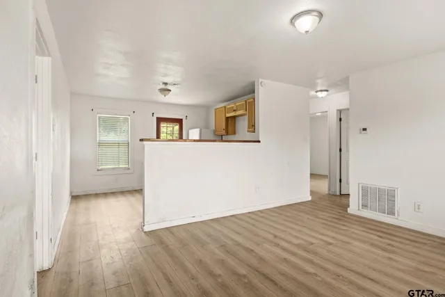 an empty room with wooden floor and windows