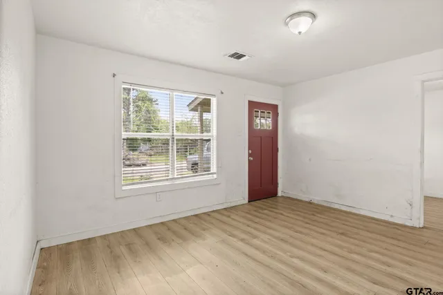an empty room with wooden floor and windows