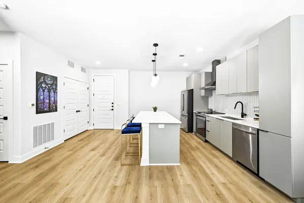 a large kitchen with stainless steel appliances granite countertop a lot of cabinets and wooden floor
