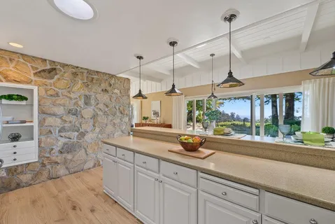 a kitchen with a sink a counter top space and living room view
