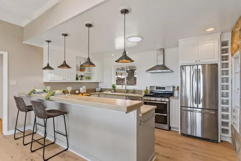 a kitchen with stainless steel appliances granite countertop a sink a stove and a refrigerator