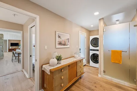 a living room with furniture a rug kitchen view and large windows