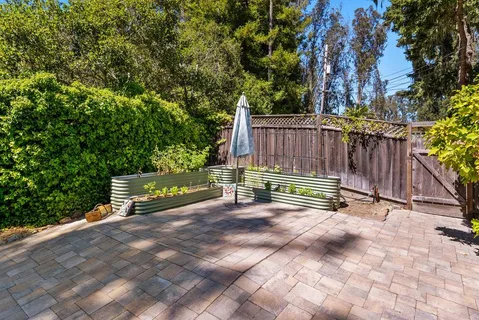 a view of a patio with table and chairs and potted plants with large tree