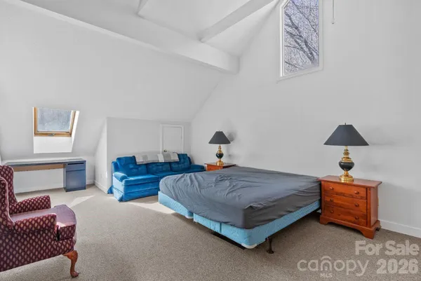 a spacious bedroom with a bed and a lamp