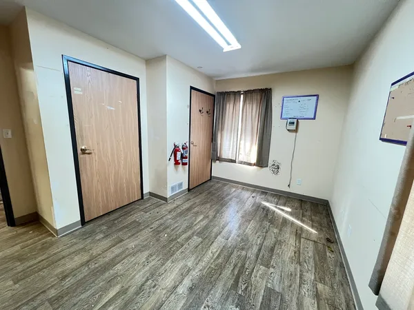 an empty room with wooden floor and windows