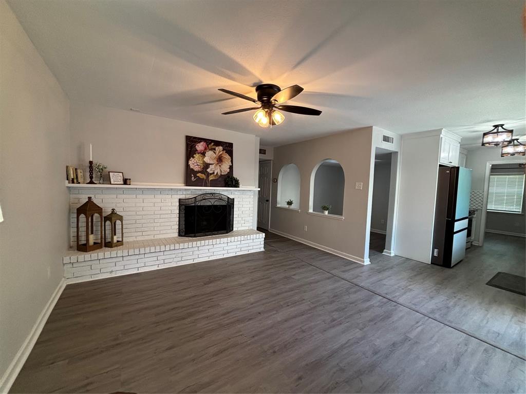 5036 Avery Lane The Colony, TX 75056 - Photo 10 of 22 a view of a livingroom with a fireplace a ceiling fan and wooden floor
