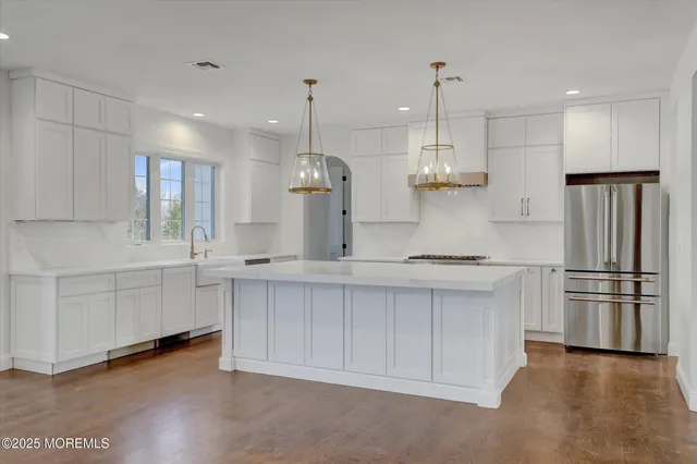 a large kitchen with kitchen island a stove a sink a center island and wooden floor