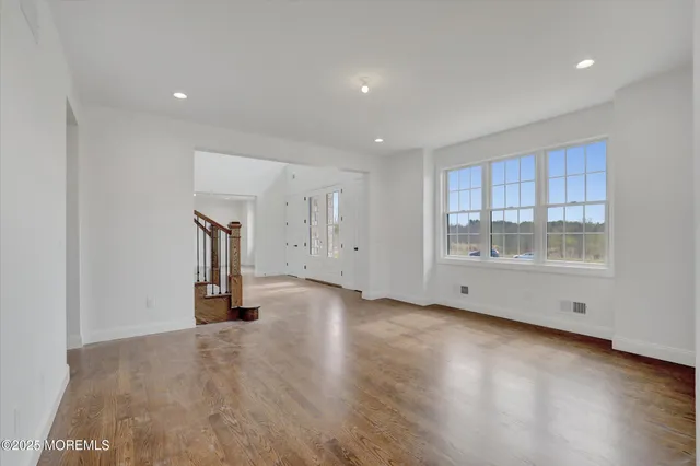 a view of empty room with wooden floor and windows