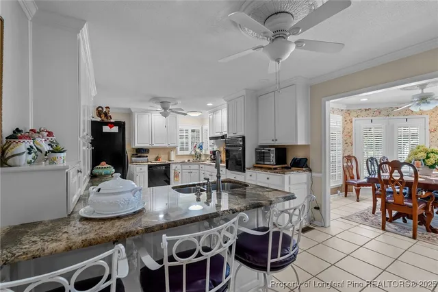 a kitchen with stainless steel appliances kitchen island granite countertop a table chairs and a refrigerator