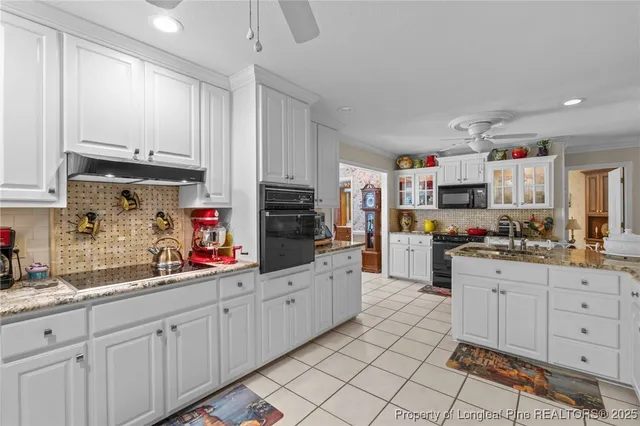 a kitchen with kitchen island granite countertop lots of white stainless steel appliances and white cabinets