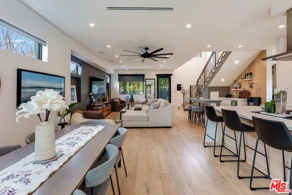 a kitchen with stainless steel appliances kitchen island granite countertop a refrigerator a stove a sink and a dining table with wooden floor