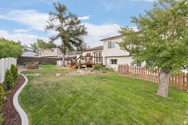 12152 Cinnamon Ridge Road Sandy, UT 84094 - Photo 34 of 51 Expansive backyard featuring a manicured lawn, multi-level wood deck, white vinyl fencing, and a raised garden bed