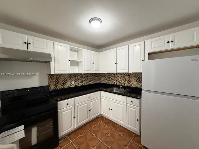 a kitchen with granite countertop white cabinets and black appliances