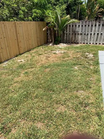 a view of backyard with wooden fence and trees