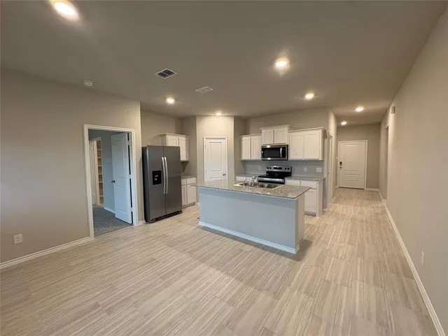 a kitchen with stainless steel appliances kitchen island granite countertop a refrigerator and a stove top oven