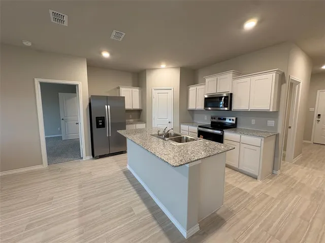 a kitchen with stainless steel appliances granite countertop a stove top oven a refrigerator and a sink