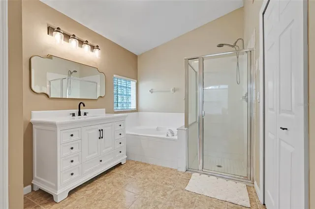 a bathroom with a double vanity sink a mirror and a bathtub