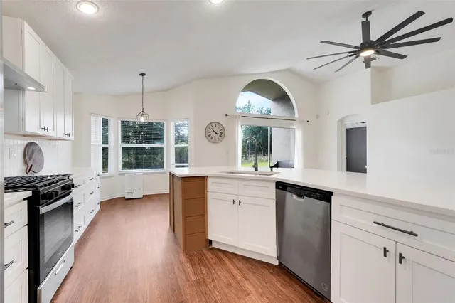 a kitchen with granite countertop a stove a sink and wooden floor