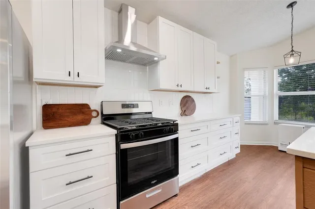 a kitchen with granite countertop white cabinets and a stove with wooden floor