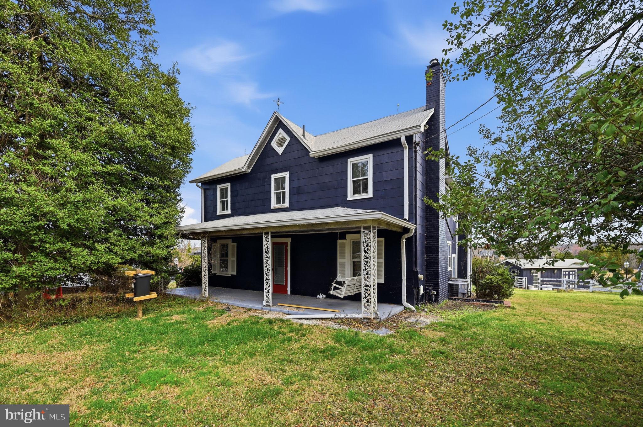 Charming blue farmhouse with lush surroundings.