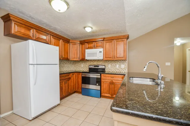 a kitchen with stainless steel appliances granite countertop a refrigerator sink stove and microwave