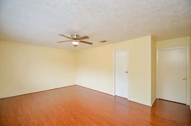 a view of a room with wooden floor and a ceiling fan