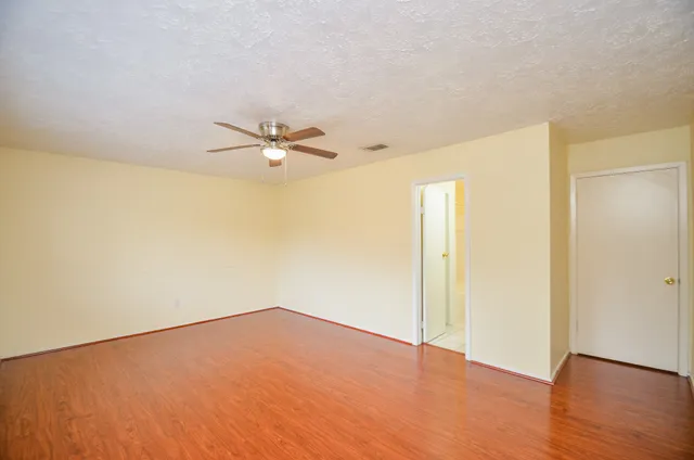 a view of a room with wooden floor and a ceiling fan