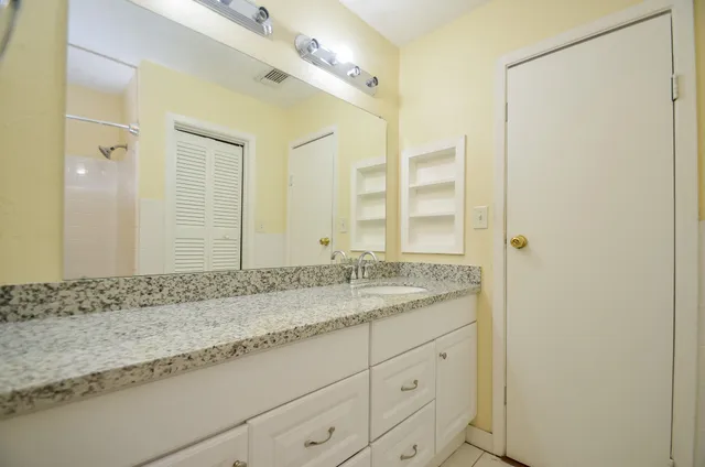 a bathroom with a granite countertop sink and a mirror