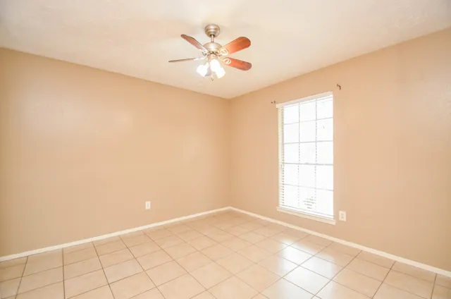 an empty room with windows and chandelier fan