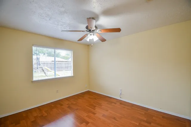 an empty room with a window and a fan