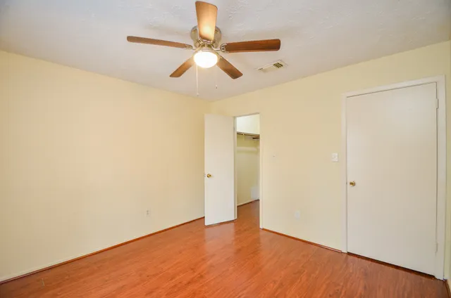an empty room with wooden floor and fan