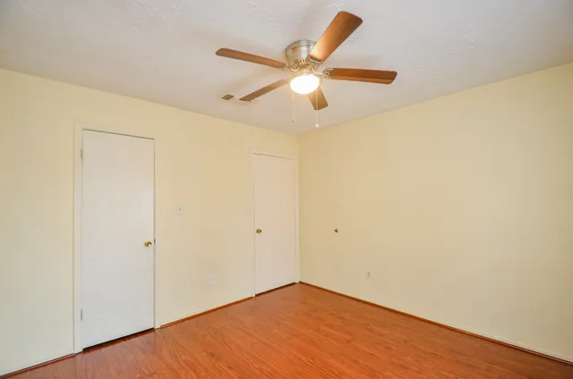an empty room with ceiling fan and wooden floor
