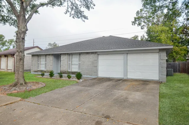 a view of a house with a yard and large tree
