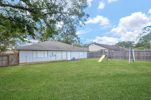 a view of a house with a yard and a large tree
