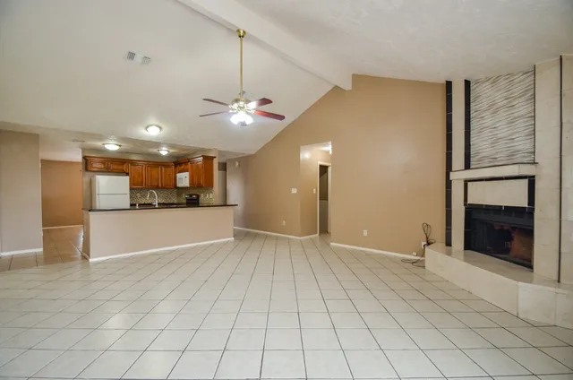 a view of an empty room and a kitchen