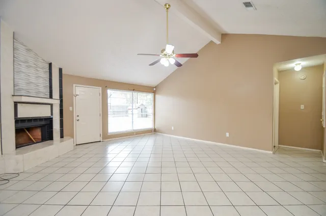 a view of an empty room with a fireplace and a chandelier fan
