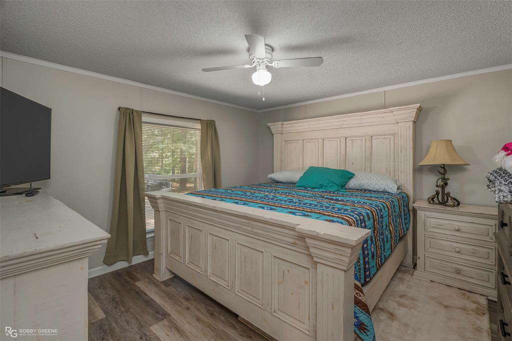 8273 Godfrey Road Shreveport, LA 71129 - Photo 14 of 27 Wood-finish flooring, ceiling fan with integrated lighting, window with light-filtering curtains, and crown molding