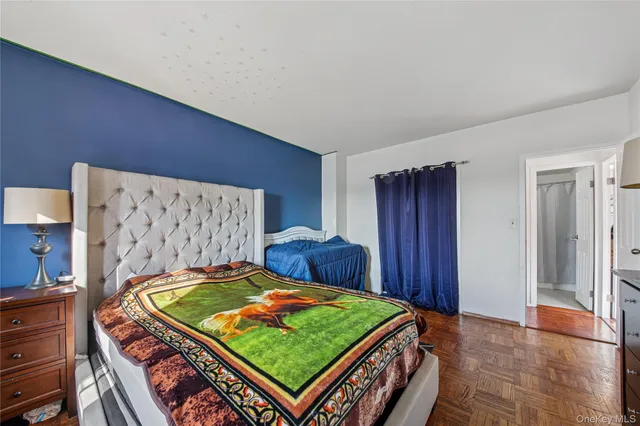 a bedroom with a bed and a dresser with wooden floor