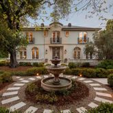 a front view of a house with a garden and lake view