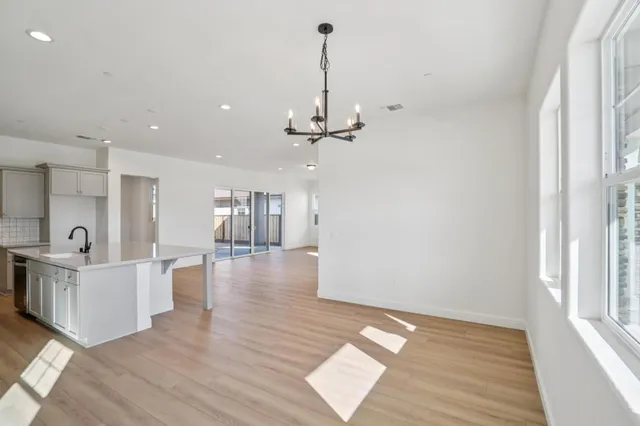 a open kitchen with stainless steel appliances granite countertop a refrigerator a stove top oven a sink dishwasher and white cabinets with wooden floor