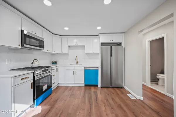 a kitchen with stainless steel appliances granite countertop a stove top oven a sink dishwasher a refrigerator and a microwave oven with wooden floor