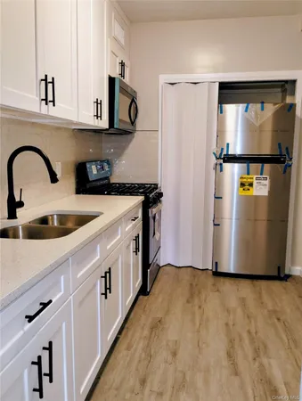 a kitchen with stainless steel appliances granite countertop a sink a stove a refrigerator a counter space and cabinets