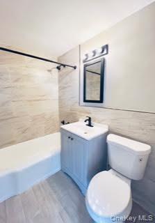 3 Fordham Hill Ovl, Unit 4H Bronx, NY 10468 - Photo 9 of 12 Full bathroom with bathtub / shower combination, vanity, tile walls, and light wood-type flooring